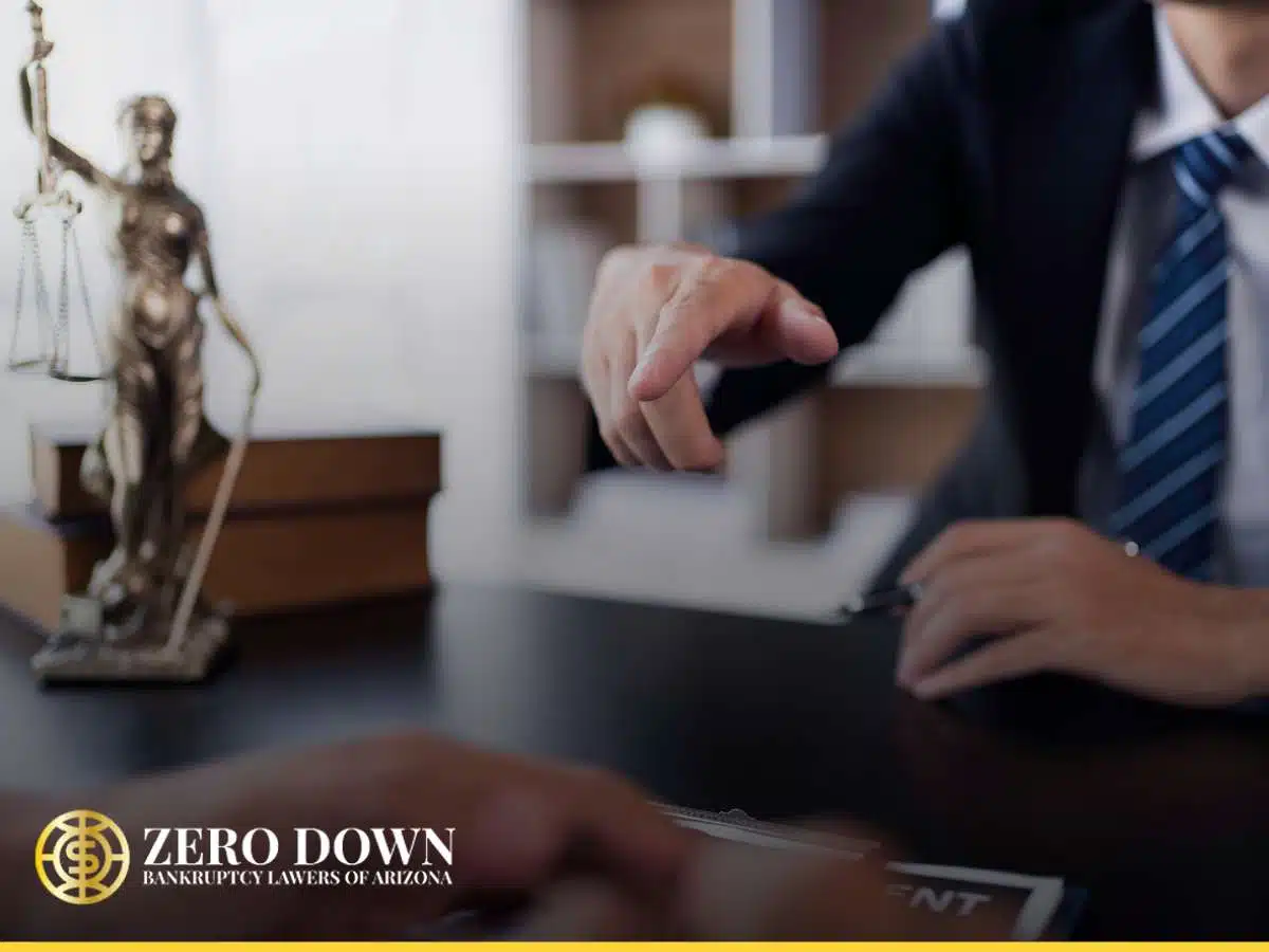  A bankruptcy lawyer in Arizona points towards a document on a desk, with a blurred statue of Lady Justice in the background.
